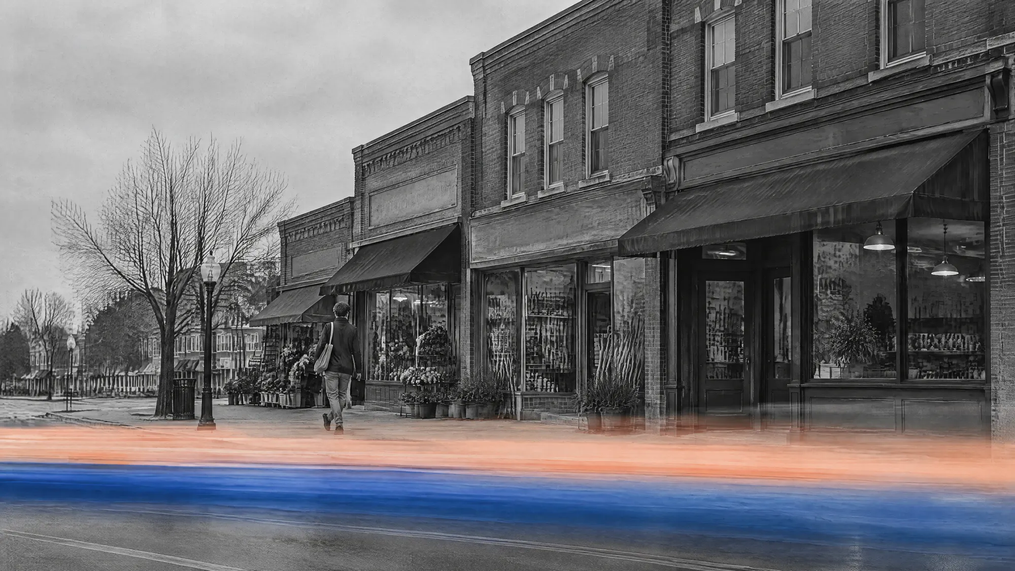 A sales rep with a tablet walking along a row of independent brick storefronts on a small-town main street